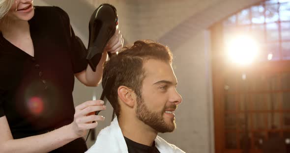 Smiling man getting his hair dried with hair dryer