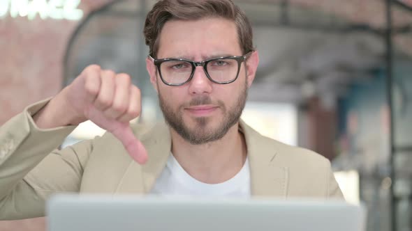 Thumbs Down By Young Man with Laptop