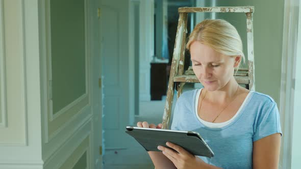 A Woman Uses a Tablet in the House Where Repairs Are Underway. Online Order of Building Materials