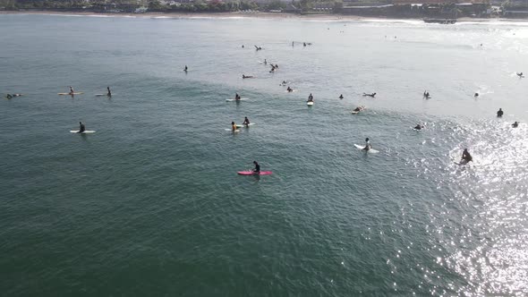 Aerial view of people surfing on waves with surfboards when vacation in Bali, Indonesia .