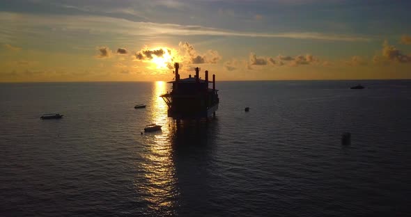 Aerial flight at stunning sunset over ocean along an oil rig in Mabul, Malaysia
