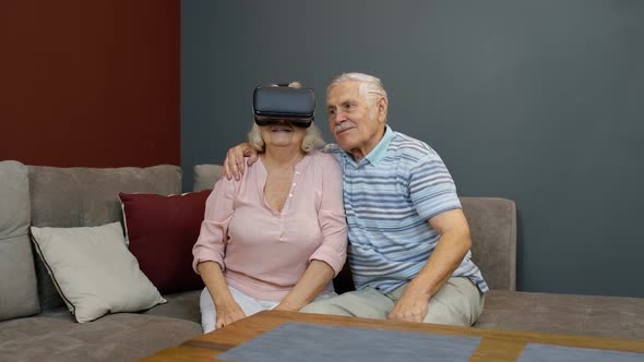 Senior Woman Playing Game in Virtual Reality Headset Glasses, Man Laughing with Her Action at Home