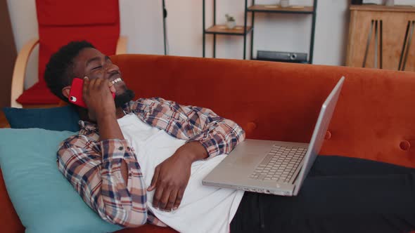 Young Man Using Laptop Computer Sitting on Sofa Working Online Shopping From Home Office