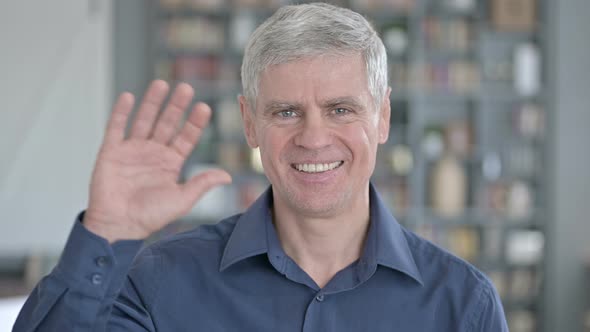 Portrait of Middle Aged Man Waving at Camera in Office