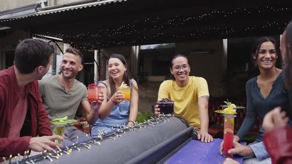 The Group of People are Having Fun and Laughing Together on the Terrace of the Bar Drinking Colorful