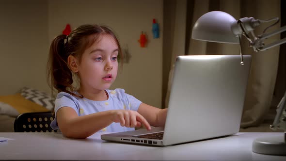 Little Girl Studying at an Online School on a Laptop