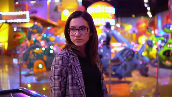 A Young Woman Is Standing in an Amusement Park. The Camera Moves Closer To the Girl. Park for