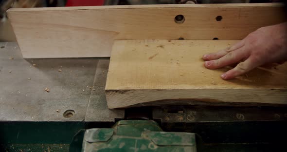 Worker in a Woodworking Workshop Takes a Board and Puts It on a Machine in Woodworking Workshop of a