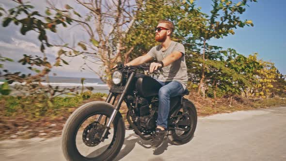 Motorcyclist Driving His Motorbike on the Ocean Beach