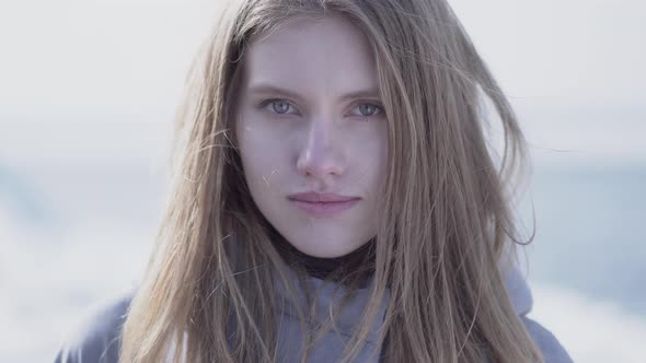 Close-up Portrait of Beautiful Young Blond Woman with Long Hair and Blue Eyes Looking in the Camera