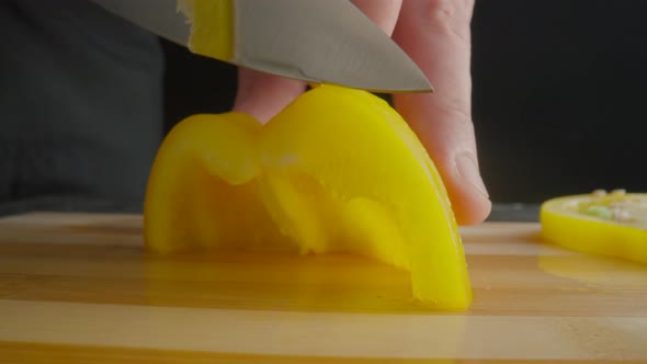 Hands of Man with Knife Slicing Yellow Sweet Pepper Into Semiring