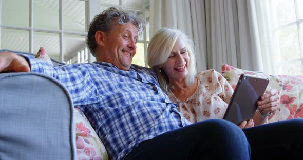 Senior couple using digital tablet on sofa 