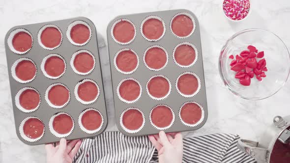 Flat lay. Step by step. Scooping cupcake batter into foil cupcake cups to bake red velvet cupcakes.