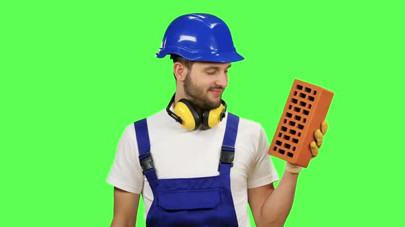 Engineer Holds a Brick in His Hand and Shows a Thumbs Up. Green Screen