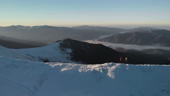 Drone Passing Couple of Hikers, Walking on Mountain Ridge in Winter