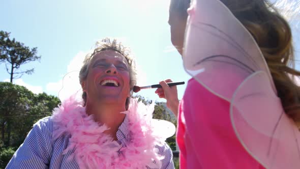 Cute daughter in fairy costume putting makeup on her fathers face 4k