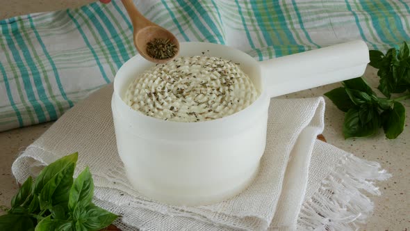 Homemade cottage cheese in the mold is sprinkled with spices