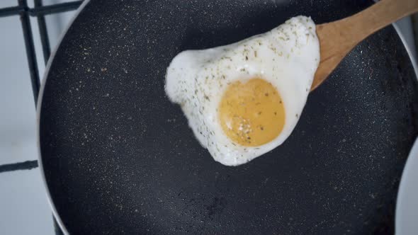 Egg with Spices is Placed on a White Plate with a Wooden Spatula Close Up