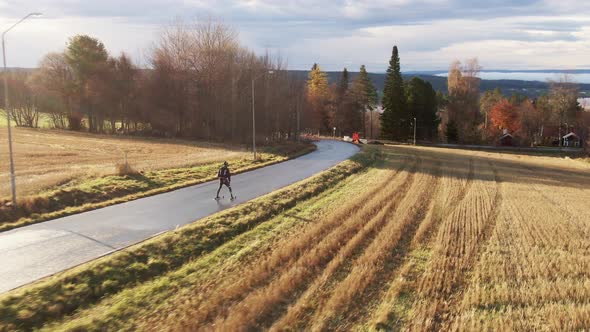 Man Skiing Down The Street Near Lake Town Ostersund, Sweden During Sunset. 4K Drone.