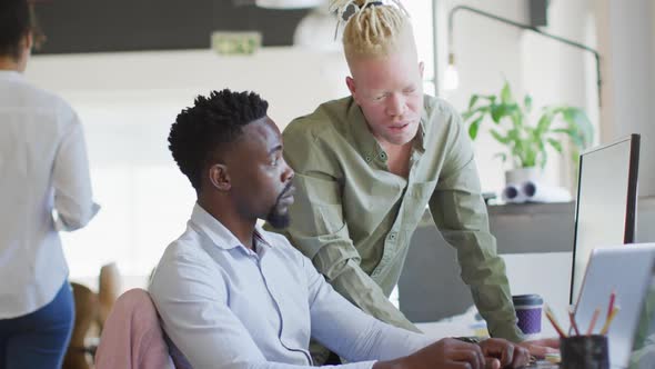 Diverse business people discussing with laptop in creative office