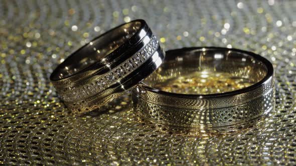 Wedding Gold Rings Lying on Shiny Glossy Surface. Shining with Light. Close-up