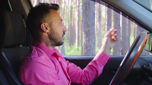 Serious Businessman Smoking a Cigarette While Driving and Talking