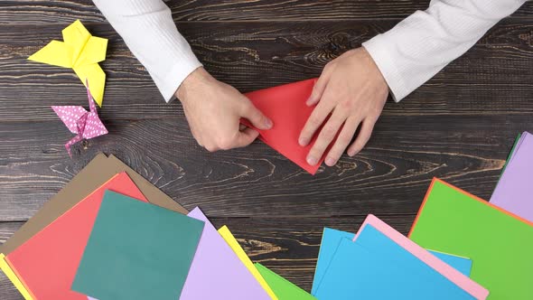 Male Hands Folding Red Paper Sheet.