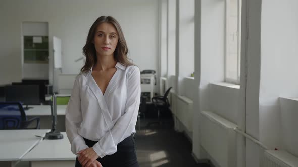 Serious Woman Stands in Office Room