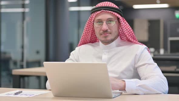 Middle Aged Arab Man with Laptop Smiling at Camera