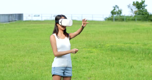 Woman watching with virtual reality device and sitting at the park 