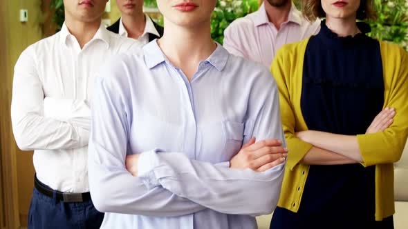 Business people with arms crossed standing in a modern office 