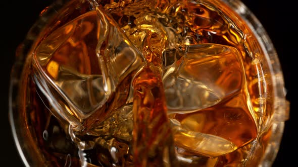 Super Slow Motion Detail Shot of Pouring Whiskey on Ice Cubes Into Glass at 1000Fps