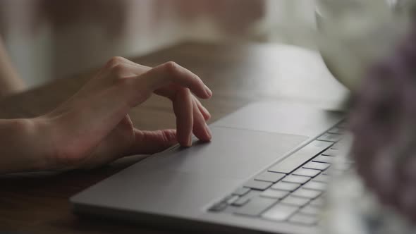 Camera Pivoting Around a Close Up of a Woman Hand Swipe on a Laptop Computer Touchpad