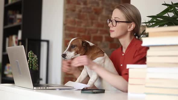 beautiful woman sitting at table with a dog and working in her home office