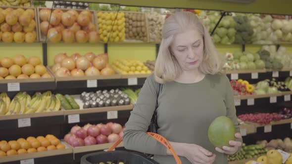 Portrait of Happy Confident Caucasian Woman Buying Fruits in Grocery. Senior Blond Housewife Putting