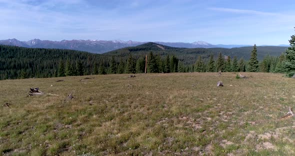 A close to the ground flight rises to see the forests and peaks of the Colorado Rocky Mountains near