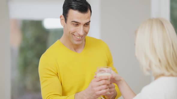 Smiling Handsome Middle Eastern Man Giving Milk Shake To Caucasian Blond Woman and Toasting