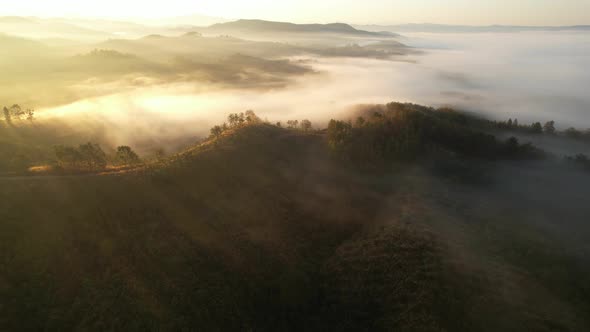 4K aerial view over mountain at sunrise in heavy fog. golden morning sunlight
