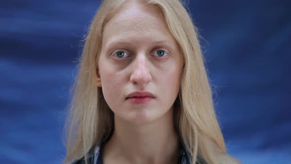 Close Up View of Young Woman with Blue Eyes Wearing Shirt and Looking To Camera. Unhappy Female