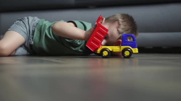 Caucasian Preschooler Boy Kid Child Playing Toy Car Truck on Floor Livingroom