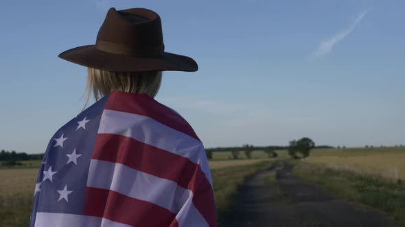 Woman in USA flag and hat on country road