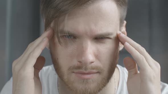 Face of Stressed Caucasian Brunette Man Rubbing Temples in Slow Motion. Close-up Portrait of Anxious