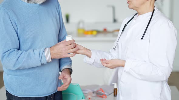 Unrecognizable Caucasian Doctor Passing Medication to Male Patient Indoors