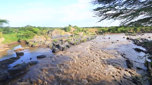 Shallow brown muddy Mara River rapids in Masai Mara, Kenya