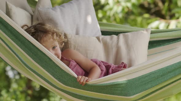 happy smiling little girl waving hello, child with blue eyes and curly hair enjoys playing looking a