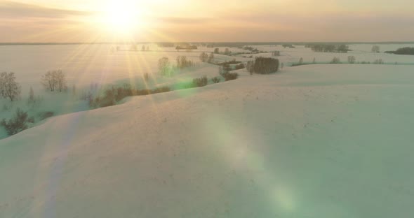 Aerial View of Cold Arctic Field Landscape Trees with Frost Snow Ice River and Sun Rays Over Horizon