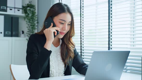 Attractive professional female happy employee worker sit on table, use mobile phone work in office.