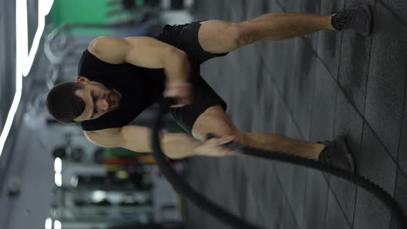 Attractive Muscular Man Working Out in the Gym Using Battle Ropes