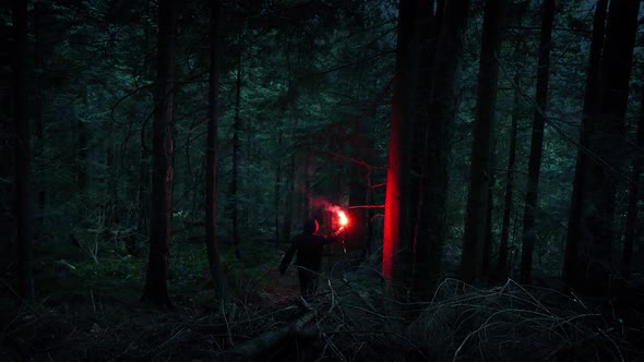 Man With Flare Descends Forest Slope