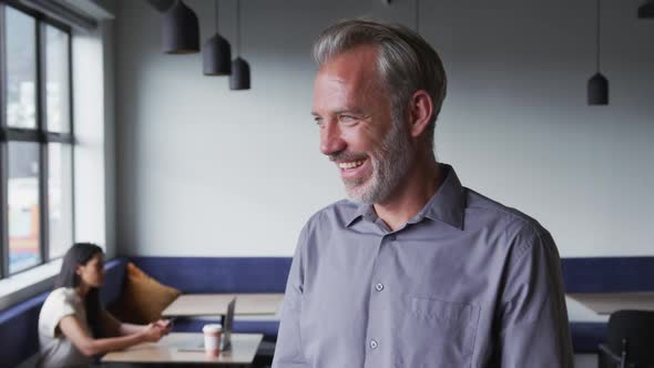 Portrait of caucasian businessman looking at camera and smiling in modern office